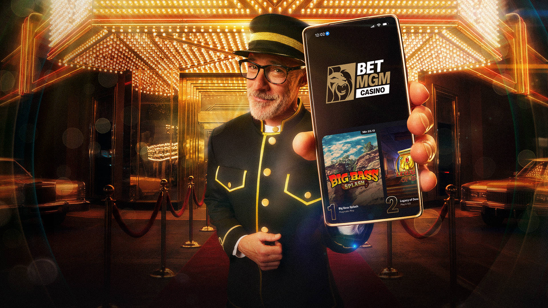 A doorman standing in front of a casino entrance holding up a smartphone with the BetMGM casino app