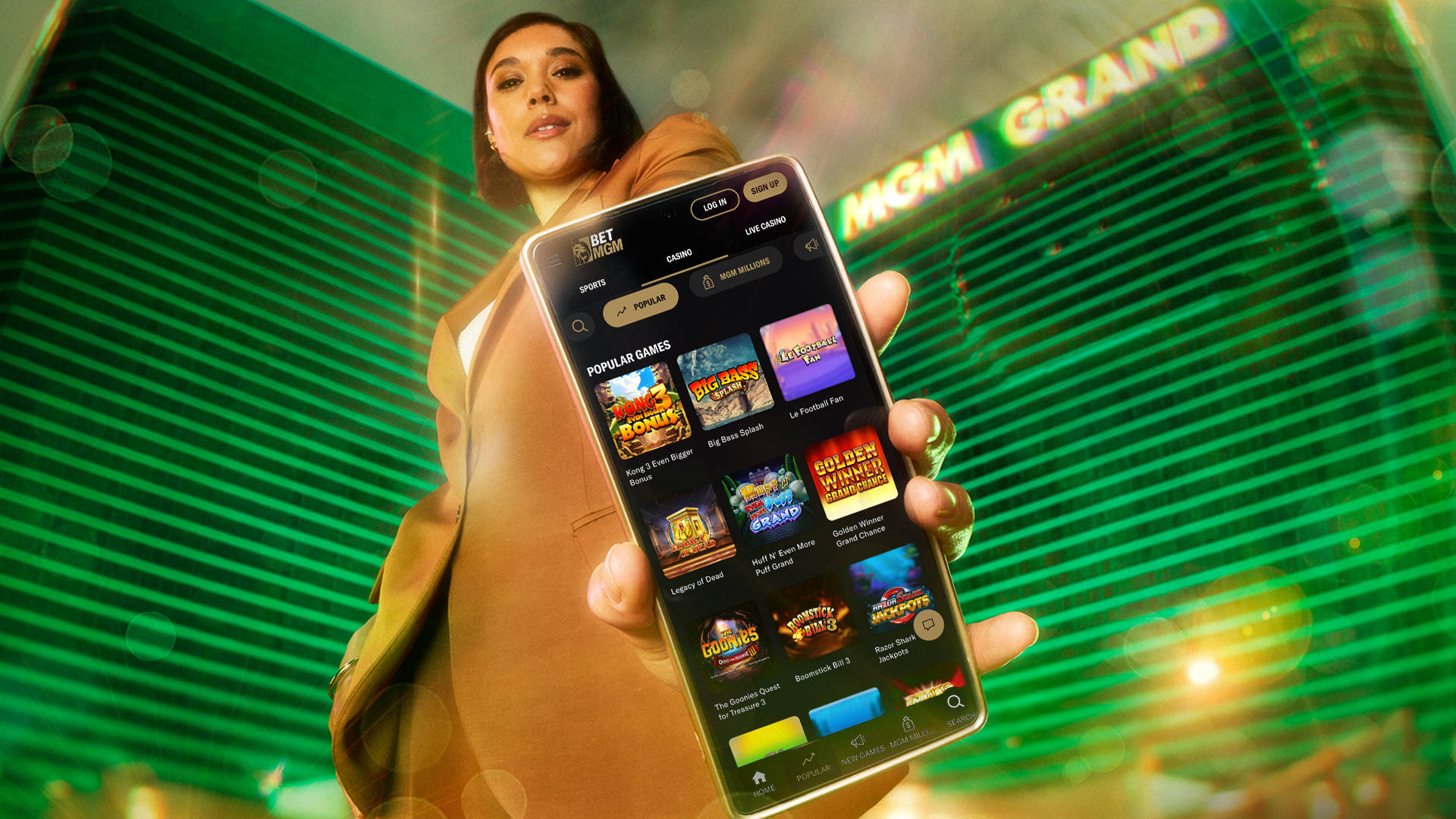 person stood in front of the MGM Grand holding up a smartphone with BetMGM's casino games