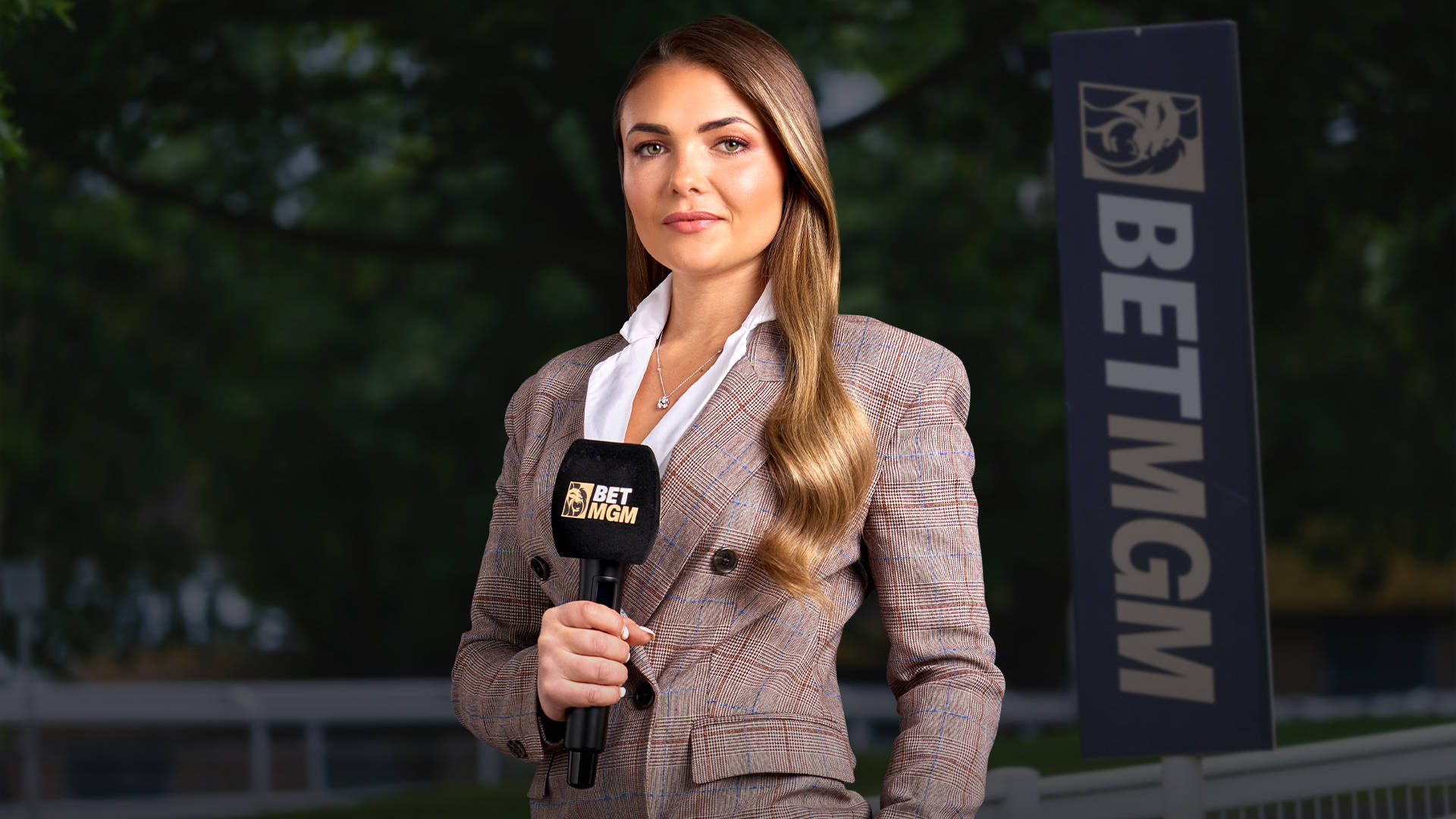 Woman holding a BetMGM microphone in front of a BetMGM sign.
